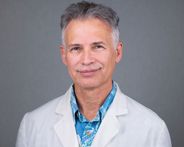 A man in white lab coat and blue shirt.