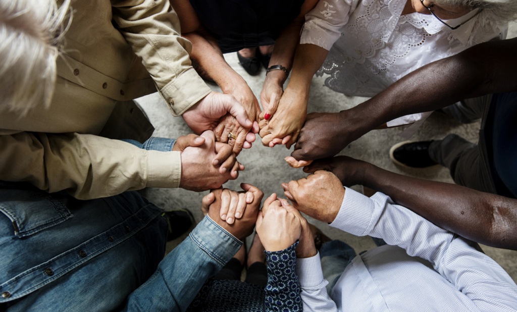 A group of people holding hands in the middle of a circle.