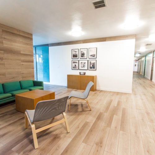 A room with wooden floors and green chairs.