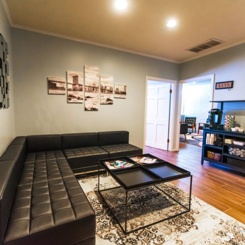 A living room with black leather furniture and a white rug.