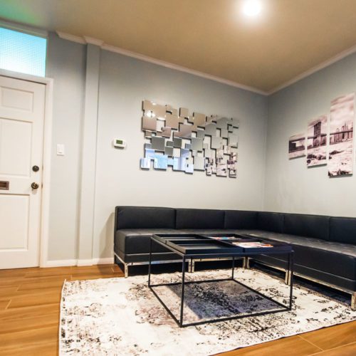 A living room with black leather furniture and a white rug.