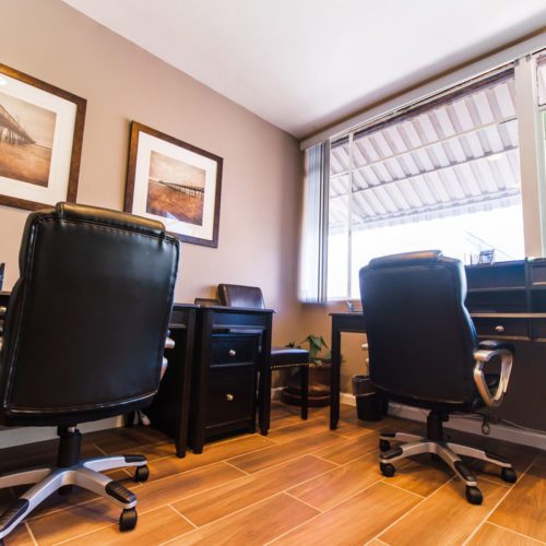 Two black chairs in a room with a window.