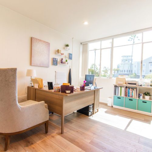 A living room with a desk and chair in it