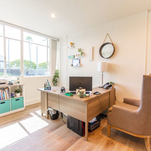 A living room with a desk and chair in it