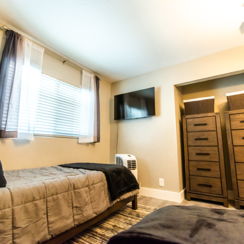 A bedroom with two beds and a television.