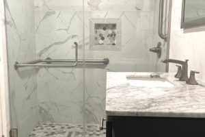 A bathroom with marble walls and floors, and a walk in shower.