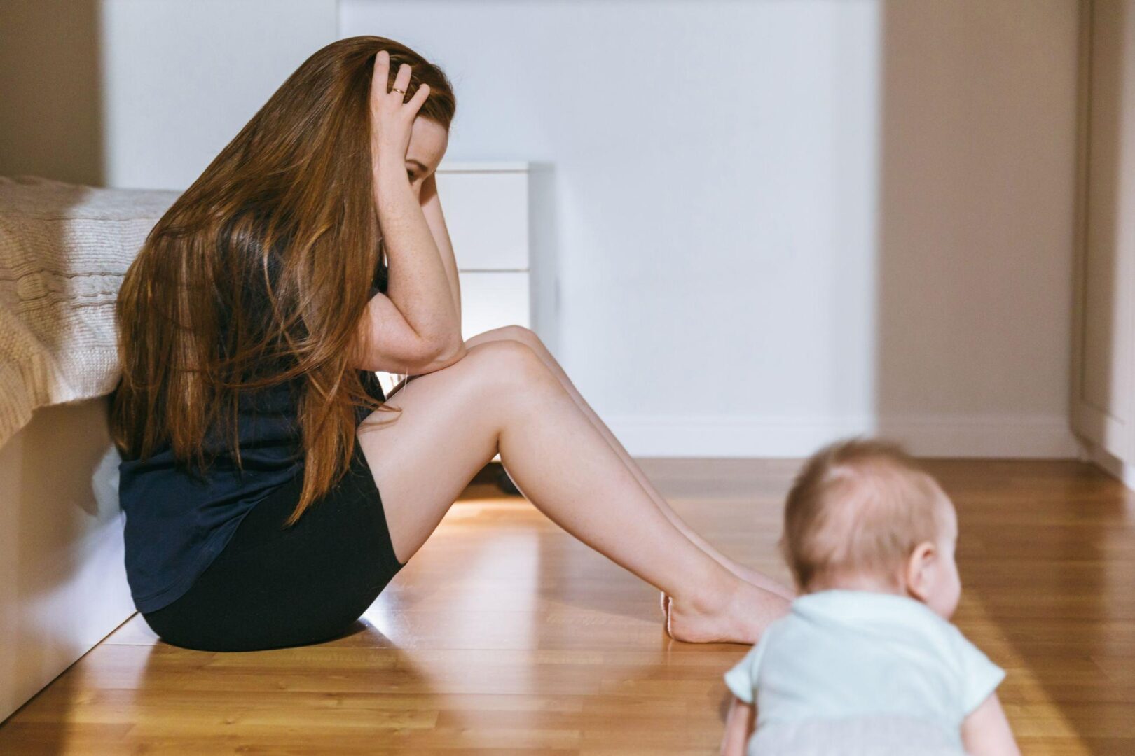 A woman sitting on the floor with her head in her hands.