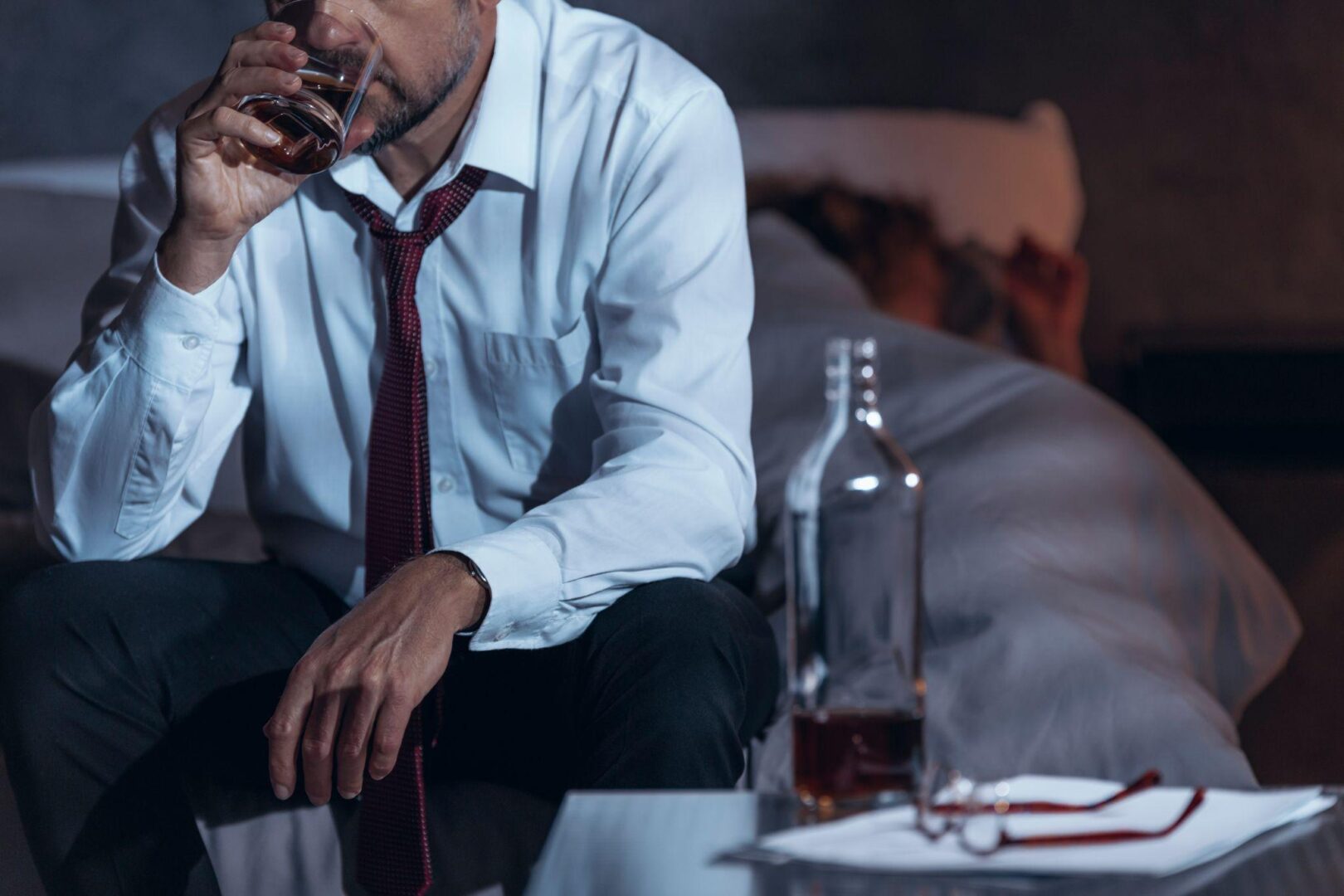A man sitting on the couch drinking alcohol.