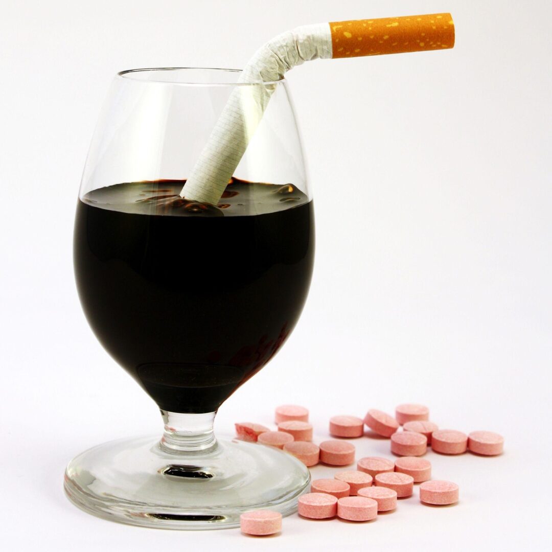 A glass of wine with cigarettes in it