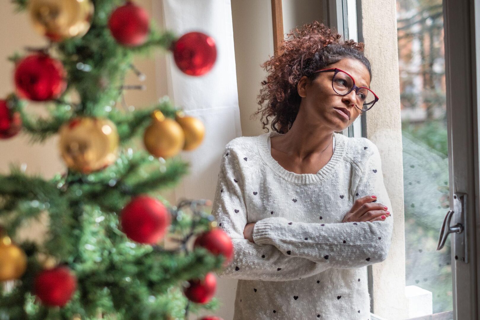 A woman standing in front of a christmas tree.