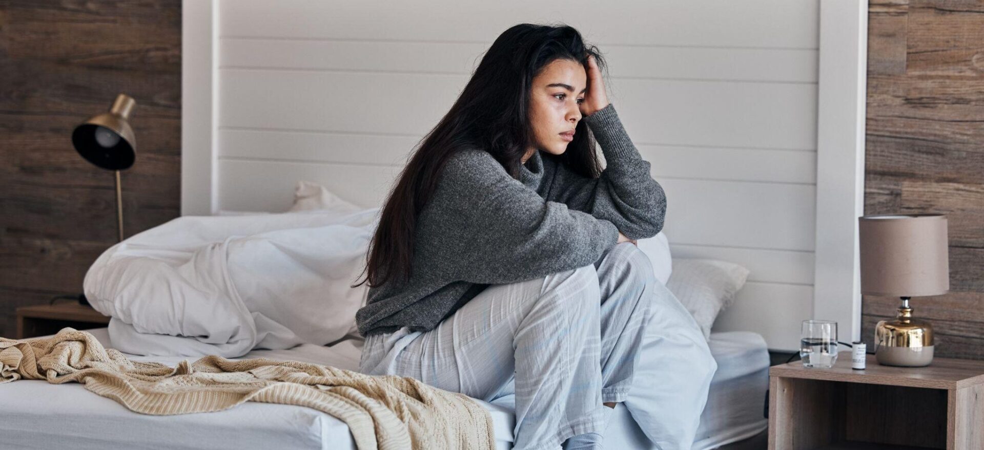 A woman sitting on top of the bed in her pajamas.