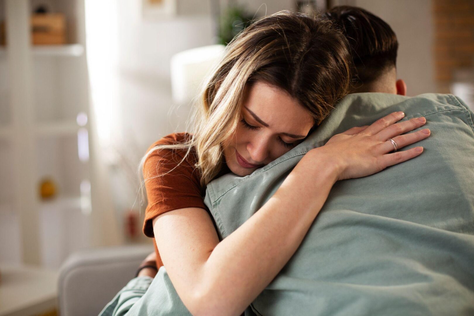 A woman hugging another person in bed.