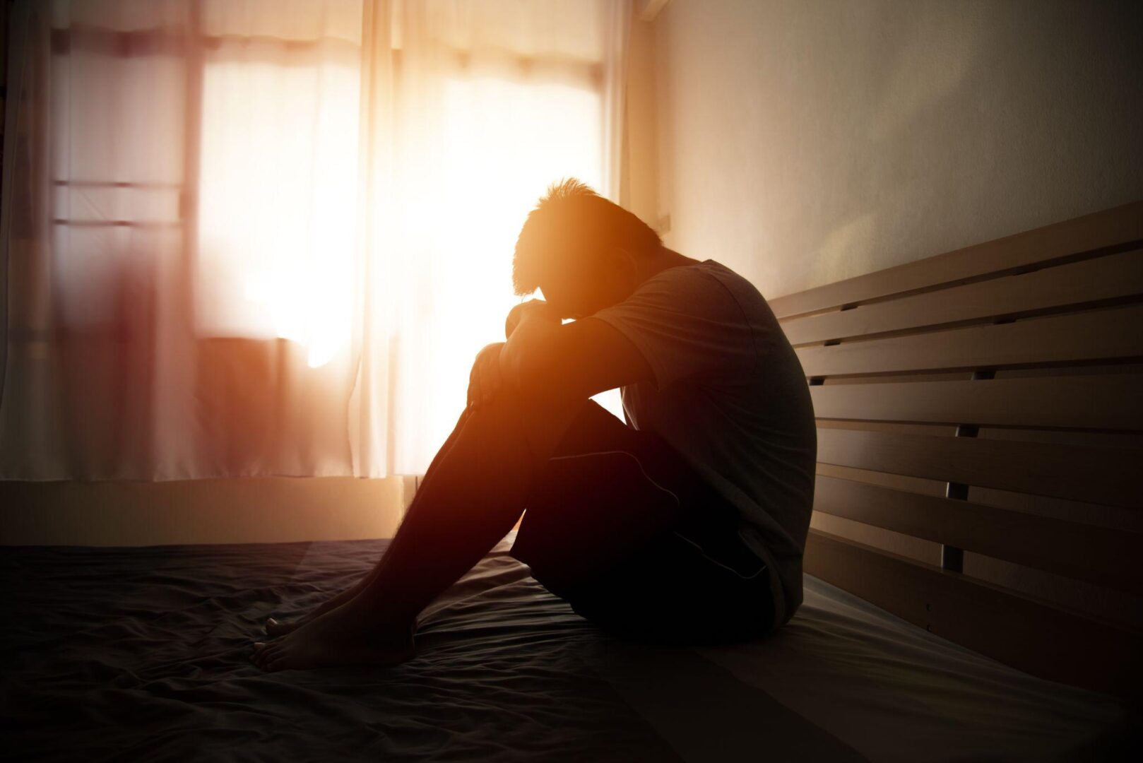 A person sitting on the ground in front of a window.