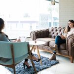 Two women sitting on a couch in front of each other.