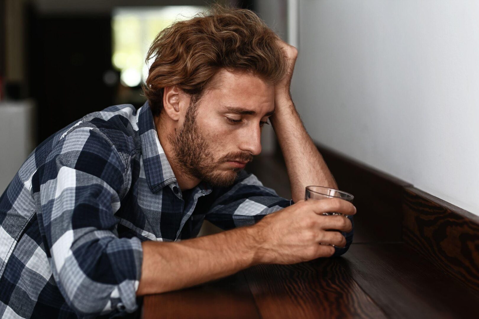 A man sitting on the edge of a bench looking at his phone.