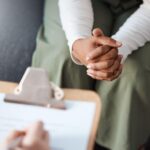 A person sitting in front of another person holding their hands.